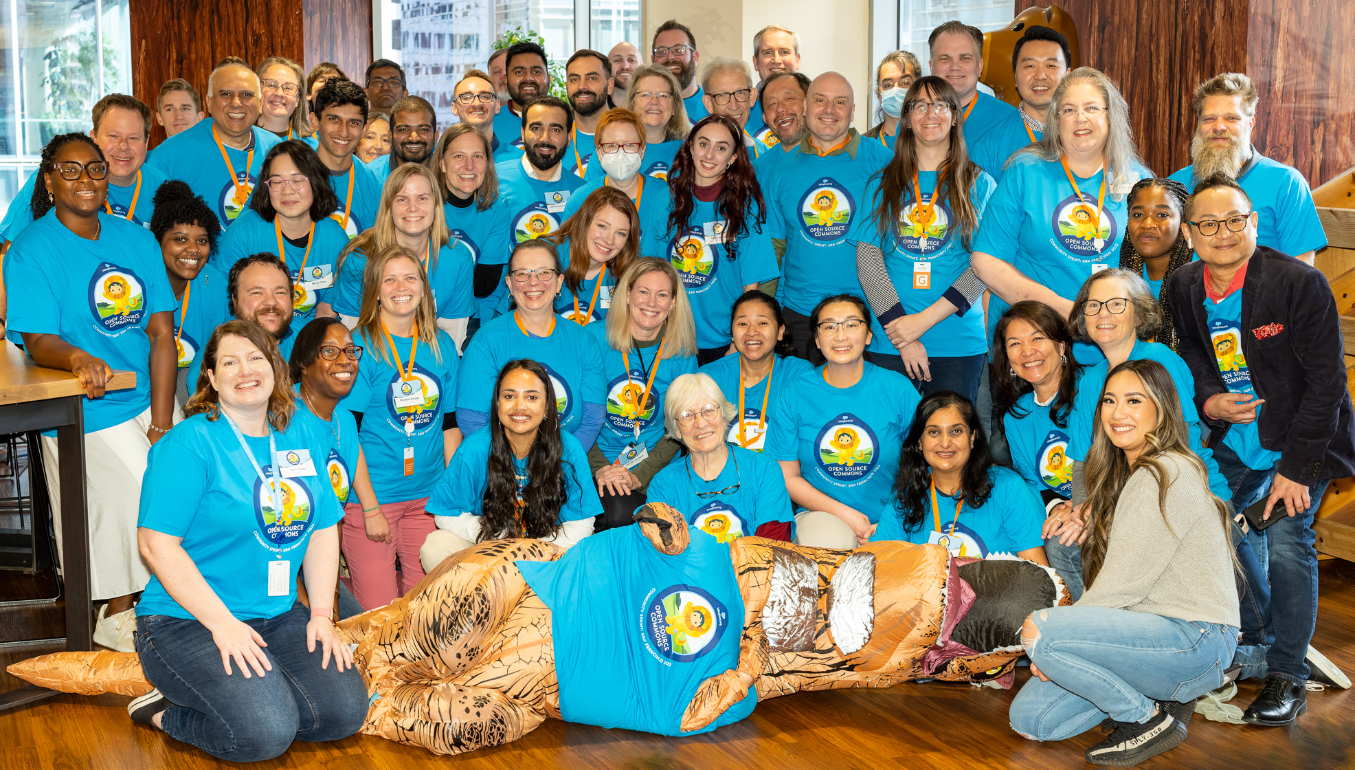 Group shot of November 2022 Sprint event attendees all wearing matching blue t-shirts. Sprinty the t-rex mascot is also in the picture